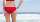 Frau in rotem Bikini am Strand von hinten